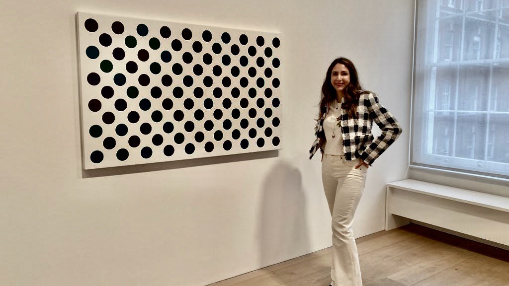 Anaïs Lellouche standing in front of Bridget Riley&#x27;s Measure for Measure, 2021. Installation view, Bridget Riley: Past into Present, 2021, at David Zwirner, Grafton Street, UK.Courtesy of the artist, Anaïs Lellouche and David Zwirner.